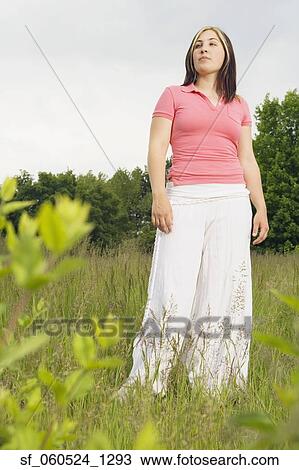 Stock Image - Young woman standing in meadow. Fotosearch