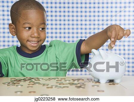 African boy putting change in piggy bank View Large Photo Image Stock Photo - African boy putting change in piggy bank. Fotosearch
