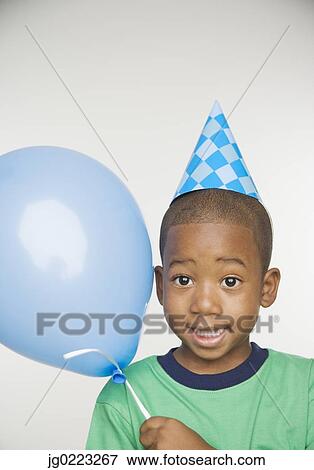 Stock Photo - African boy wearing party hat and holding balloon. Fotosearch
