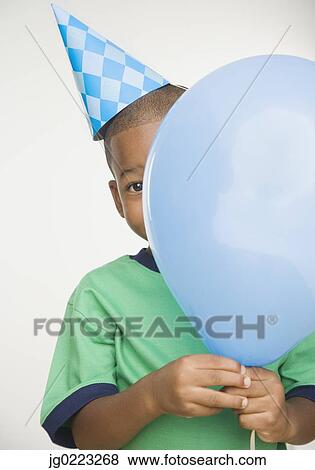 Stock Photo - African boy wearing party hat and holding balloon. Fotosearch
