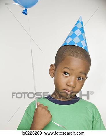 Stock Photo - African boy wearing party hat and holding balloon. Fotosearch