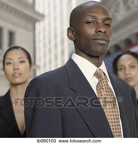 Stock Image - African businessman with businesswomen in background. Fotosearch