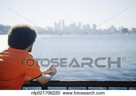 African man looking over water at city skyline View Large Photo Image Stock Image - African man looking over water at city skyline. Fotosearch