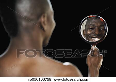 Stock Photo - African man smiling in hand held mirror. Fotosearch