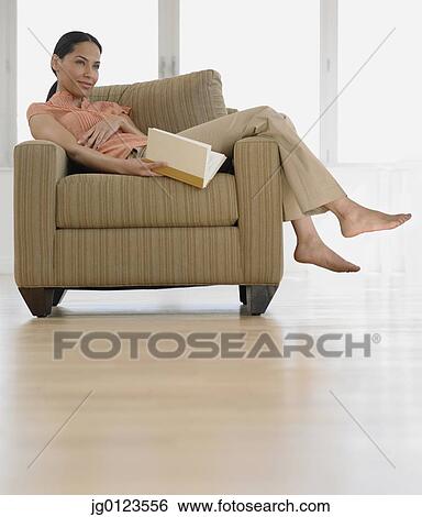 Stock Photograph - African woman in armchair holding book. Fotosearch