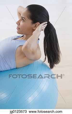 Stock Image - African woman using exercise ball. Fotosearch