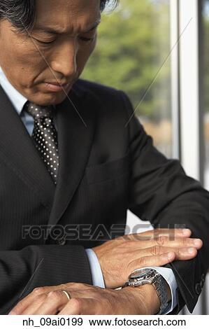 Asian businessman looking at wrist watch View Large Photo Image Stock Photo - Asian businessman looking at wrist watch. Fotosearch