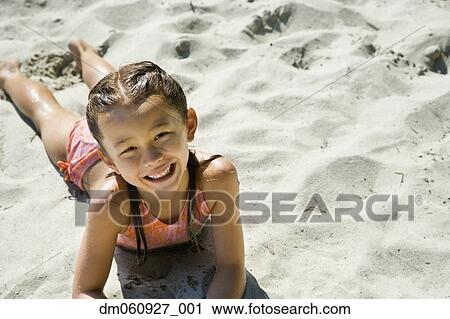 Stock Image - Asian girl laying in sand. Fotosearch