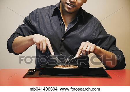 Asian man cutting meat on plate View Large Photo Image Picture - Asian man cutting meat on plate. Fotosearch