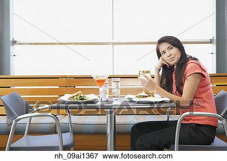 Stock Photo - Asian woman waiting at restaurant table. Fotosearch