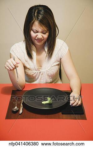Asian woman with one piece of broccoli on plate View Large Photo Image Stock Image - Asian woman with one piece of broccoli on plate. Fotosearch