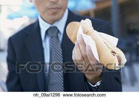 Businessman eating hot dog outdoors View Large Photo Image Stock Photograph - Businessman eating hot dog outdoors. Fotosearch