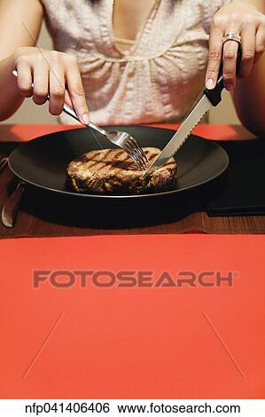 Close up of woman cutting meat on plate View Large Photo Image Stock Photograph - Close up of woman cutting meat on plate. Fotosearch