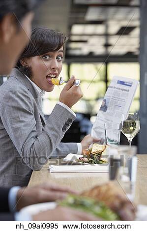 Stock Photography - Hispanic businesswoman eating at restaurant. Fotosearch