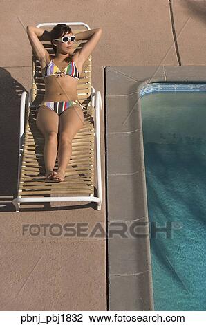 Hispanic woman sunbathing next to swimming pool View Large Photo Image Stock Image - Hispanic woman sunbathing next to swimming pool. Fotosearch