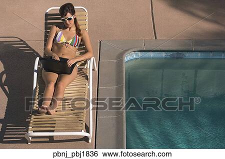 Hispanic woman typing on laptop next to swimming pool View Large Photo Image Stock Photograph - Hispanic woman typing on laptop next to swimming pool. Fotosearch