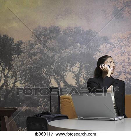 Stock Photo - Indian businesswoman with suitcase talking on cell phone. Fotosearch