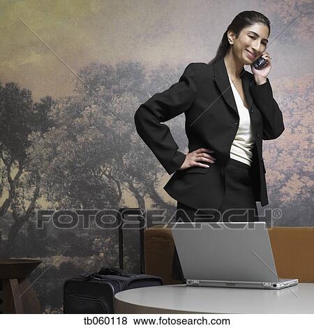 Indian businesswoman with suitcase talking on cell phone View Large Photo Image Stock Photo - Indian businesswoman with suitcase talking on cell phone. Fotosearch