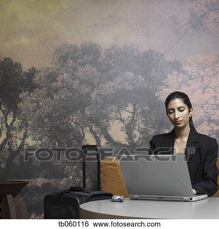 Indian businesswoman with suitcase typing on laptop View Large Photo Image Stock Photograph - Indian businesswoman with suitcase typing on laptop. Fotosearch