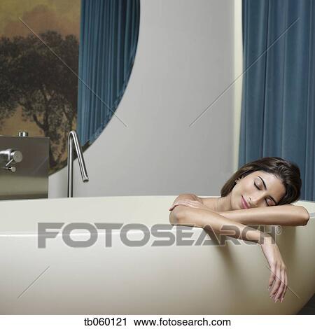 Stock Image - Indian woman in bathtub with eyes closed. Fotosearch