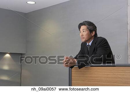 Middle-aged Asian businessman leaning on railing View Large Photo Image Stock Photo - Middle-aged Asian businessman leaning on railing. Fotosearch