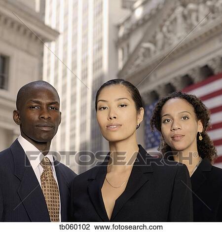 Stock Image - Portrait of businesspeople in front of American flag. Fotosearch