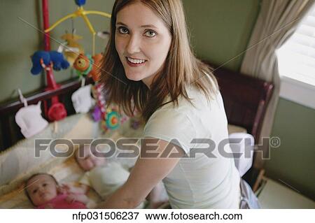 Stock Photo - Portrait of mother and twin babies in crib. Fotosearch