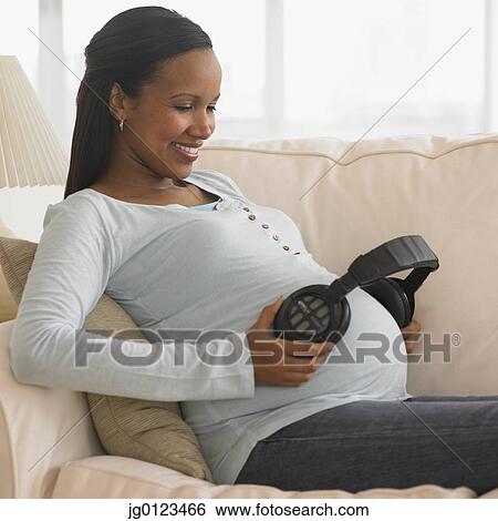 Pregnant African woman holding headphones to belly View Large Photo Image Stock Photograph - Pregnant African woman holding headphones to belly. Fotosearch
