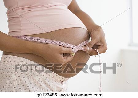 Stock Photography - Pregnant African woman measuring belly. Fotosearch