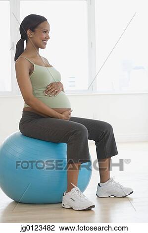 Pregnant African woman sitting on exercise ball View Large Photo Image Stock Image - Pregnant African woman sitting on exercise ball. Fotosearch