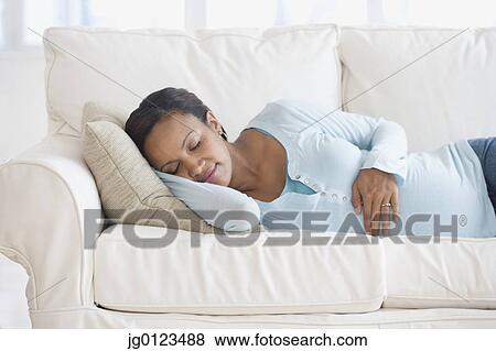 Stock Photo - Pregnant African woman sleeping on sofa. Fotosearch