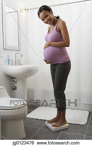 Stock Photograph - Pregnant African woman standing on scale. Fotosearch