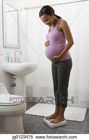 Stock Photography - Pregnant African woman standing on scale. Fotosearch