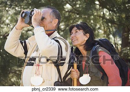 Senior couple looking through binoculars in woods View Large Photo Image Stock Photo - Senior couple looking through binoculars in woods. Fotosearch