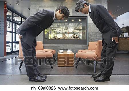Two businessmen bowing to each other in cafe View Large Photo Image Stock Photograph - Two businessmen bowing to each other in cafe. Fotosearch