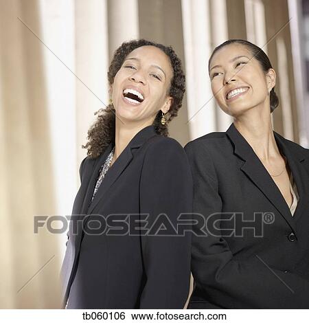 Stock Photograph - Two businesswoman laughing next to columns. Fotosearch
