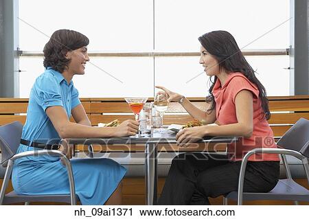 Stock Image - Two women eating at restaurant. Fotosearch