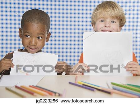 Two young boys holding up drawings View Large Photo Image Stock Photograph - Two young boys holding up drawings. Fotosearch
