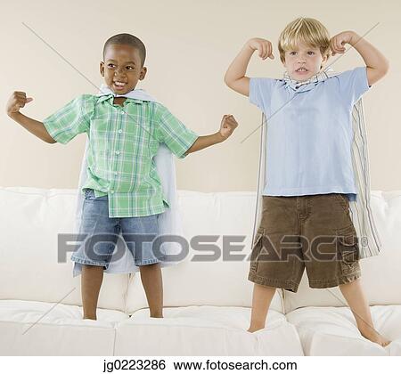 Two young boys wearing capes on sofa View Large Photo Image Stock Photograph - Two young boys wearing capes on sofa. Fotosearch