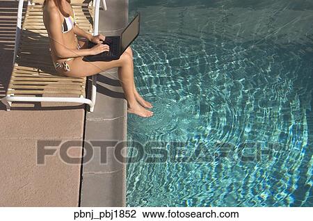 Woman typing on laptop with feet in swimming pool View Large Photo Image Stock Image - Woman typing on laptop with feet in swimming pool. Fotosearch