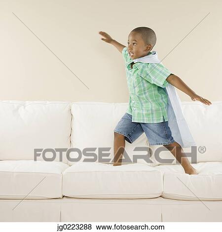 Stock Photo - Young African boy playing on sofa. Fotosearch