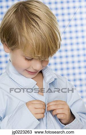 Stock Image - Young boy buttoning shirt. Fotosearch