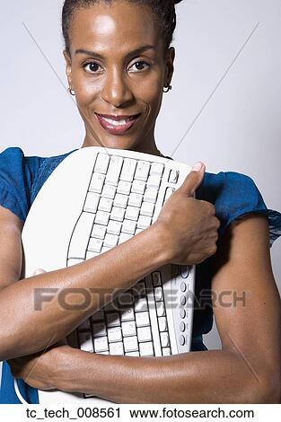 Stock Image - African businesswoman hugging computer keyboard. Fotosearch