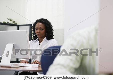 Stock Photo - African businesswoman working at desk. Fotosearch