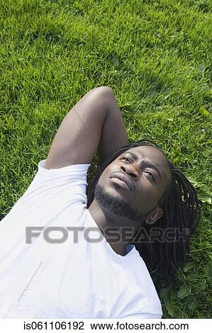 Stock Image - African man laying in grass. Fotosearch