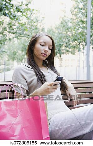 African woman looking at cell phone on park bench View Large Photo Image Stock Photography - African woman looking at cell phone on park bench. Fotosearch