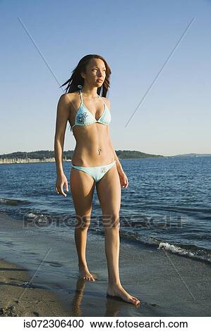 Stock Image - African woman walking on beach. Fotosearch