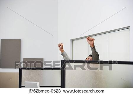 Stock Image - Asian businessman cheering in cubicle. Fotosearch