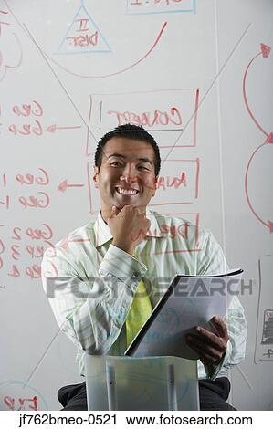 Stock Image - Asian businessman looking at flow chart. Fotosearch