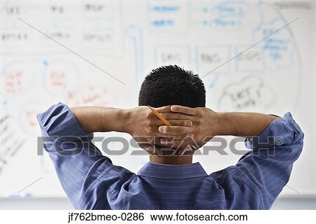 Stock Photograph - Asian businessman looking at whiteboard. Fotosearch